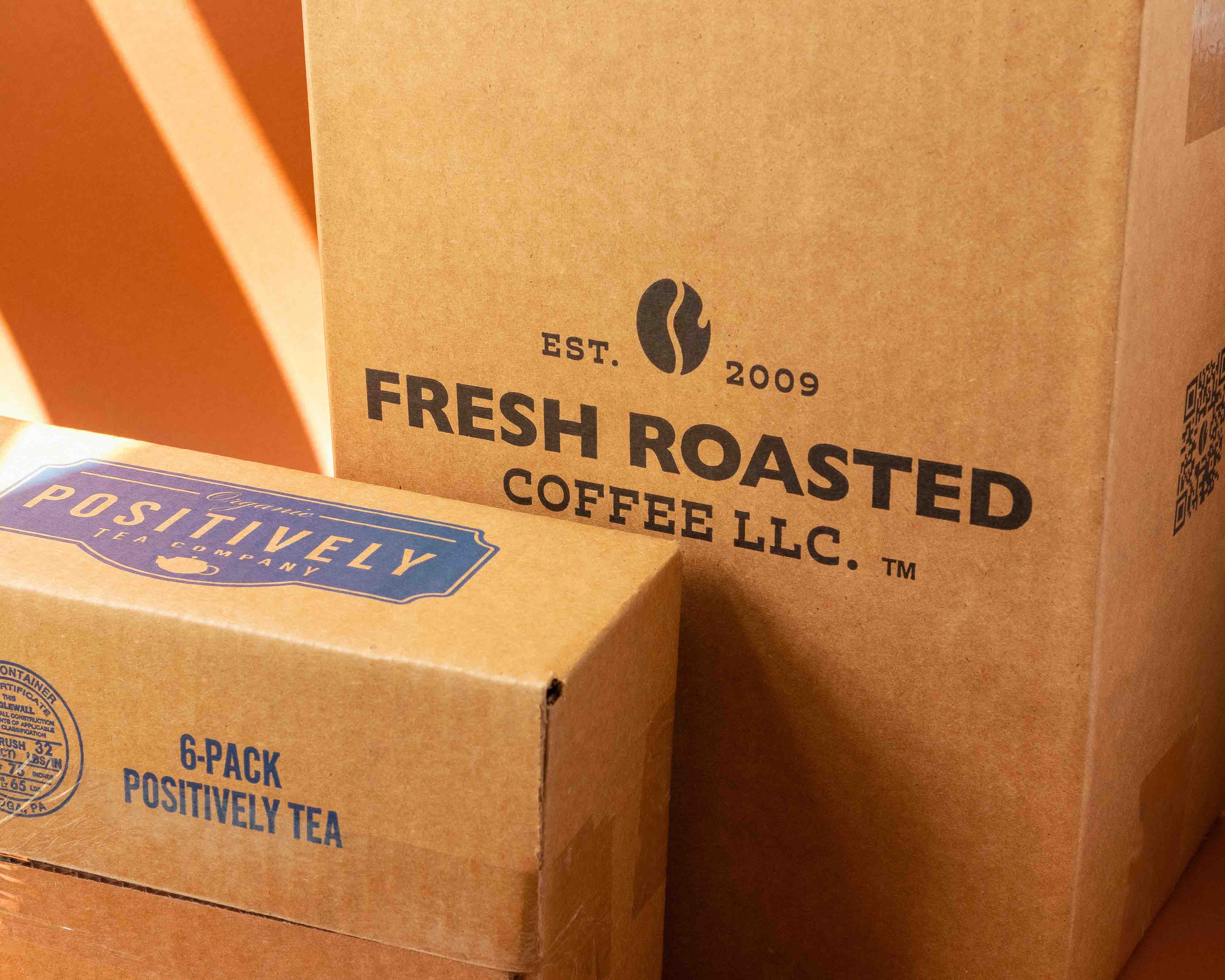 Cardboard box with Fresh Roasted Coffee logo and cardboard box with Positively Tea logo