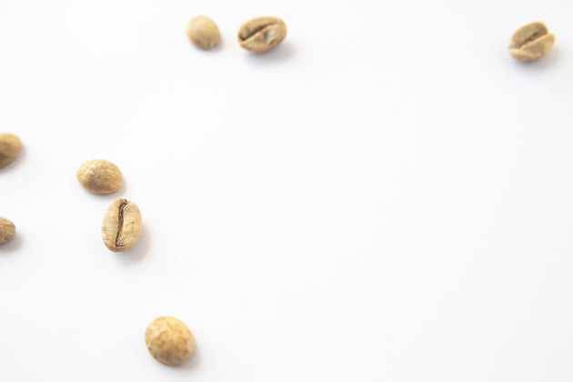 Green, unroasted coffee beans on a white background.